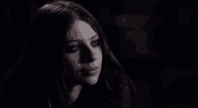 a close up of a woman 's face in a dark room with her eyes closed .