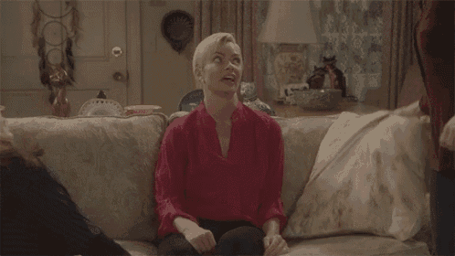 a woman in a red shirt is sitting on a couch talking to another woman .