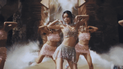 a woman in a crop top and skirt is surrounded by other women