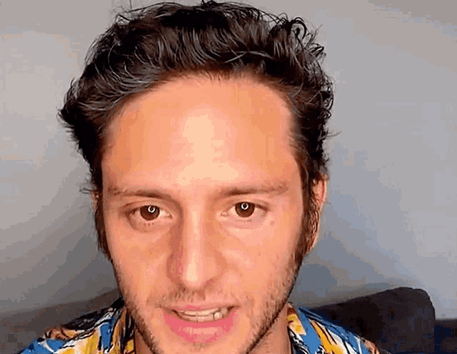 a close up of a man 's face with a beard wearing a colorful shirt