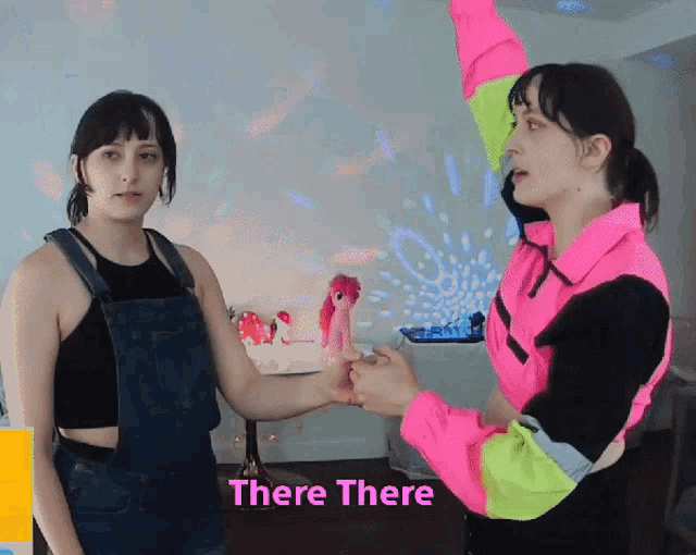 two women are holding hands with the words " there there " behind them