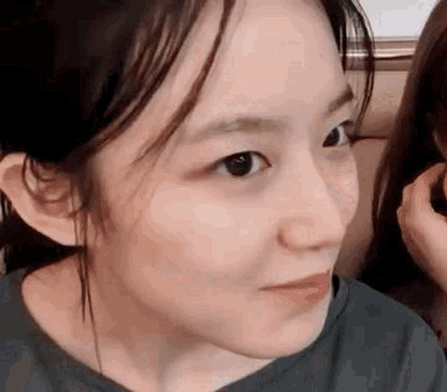 a close up of a woman 's face making a funny face while sitting next to another woman .