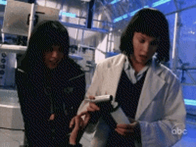 two women in lab coats are looking at a piece of paper with the abc logo in the background
