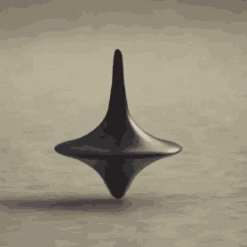 a black spinning top is spinning on a table .