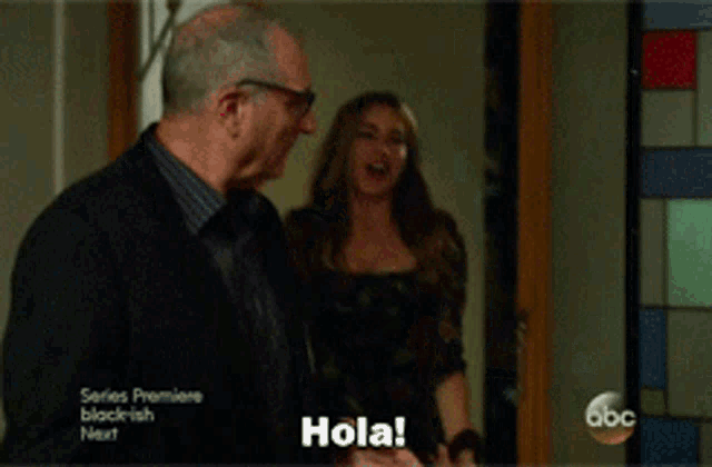 a woman is standing in front of a door with a man and says hola