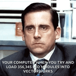 a man in a suit and tie is sitting at a desk in front of a computer screen .