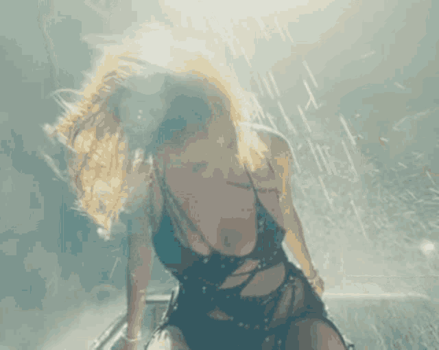 a woman with long blonde hair is dancing in the rain