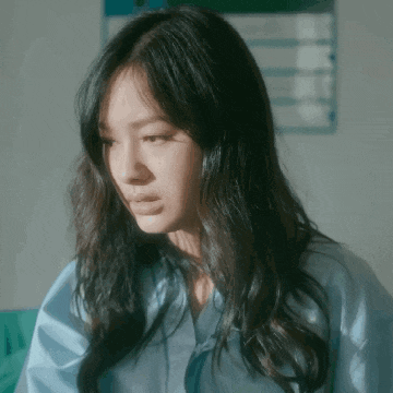a woman with long dark hair is wearing a blue shirt and looking down .