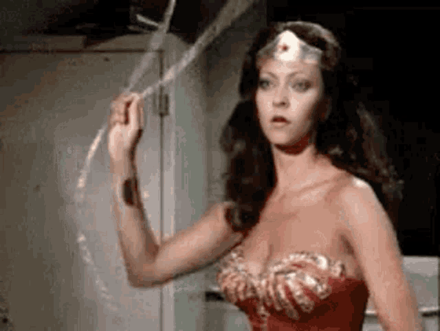 a woman in a wonder woman costume is holding a rope in her hands .
