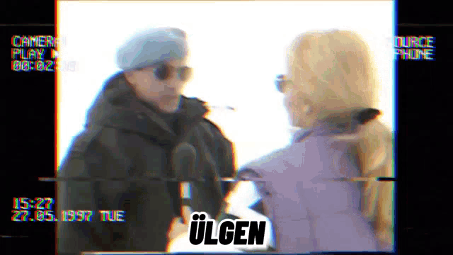 a man and a woman are standing next to each other with ulgen written on the bottom right