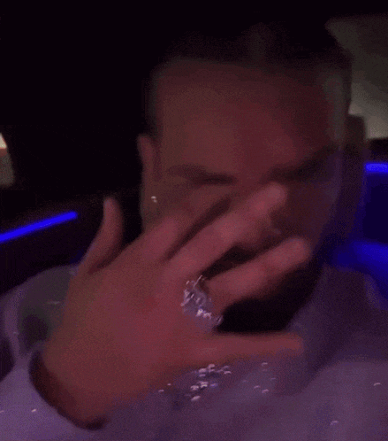 a man with a ring on his finger is crying in a car .
