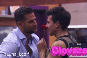 a man is holding a red rose in front of another man with the word clovazo on the bottom right