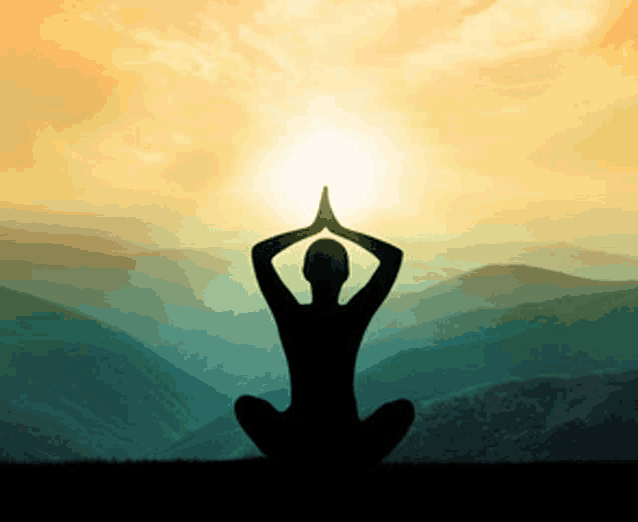 a silhouette of a person sitting in a lotus position in front of mountains