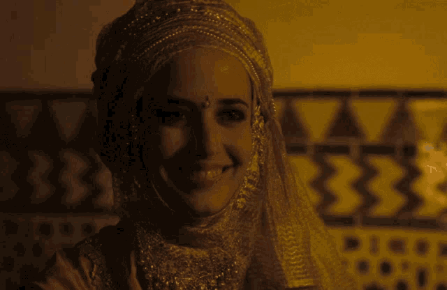 a woman wearing a veil and a headpiece smiles for the camera