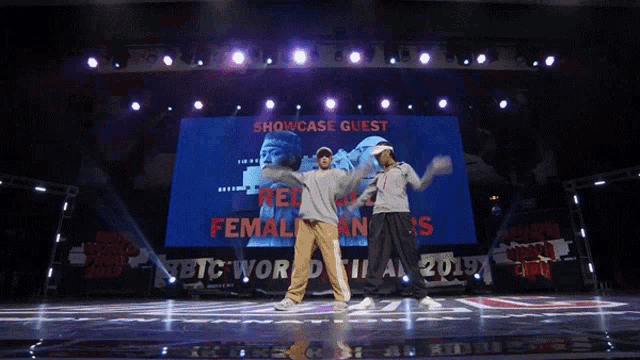 two people are dancing on a stage with a showcase guest sign behind them