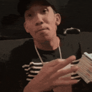 a man wearing a hat and striped shirt is holding a stack of cards in his hands