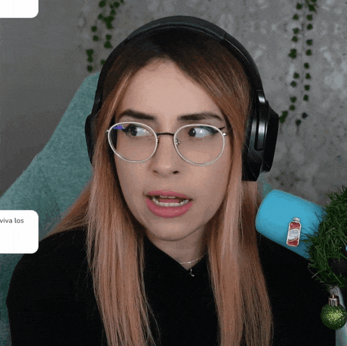 a woman wearing glasses and headphones has a sticker on her arm that says " viva los "