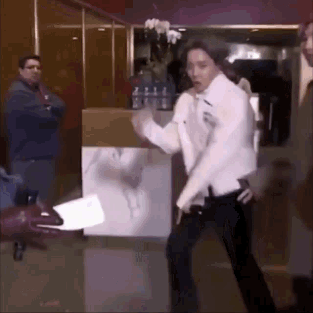 a man in a white shirt and black pants is dancing in front of a sign that says 2111