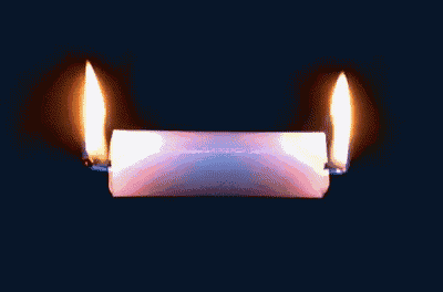 two candles are lit on a black background and one of them is white