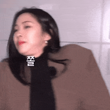 a woman wearing a brown coat and a black scarf is making a face .