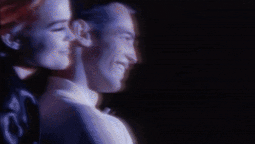 a man and a woman are looking at each other and smiling .