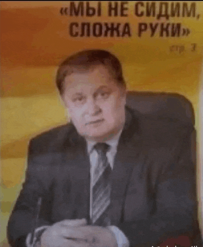 a man in a suit and tie is sitting in front of a yellow wall .