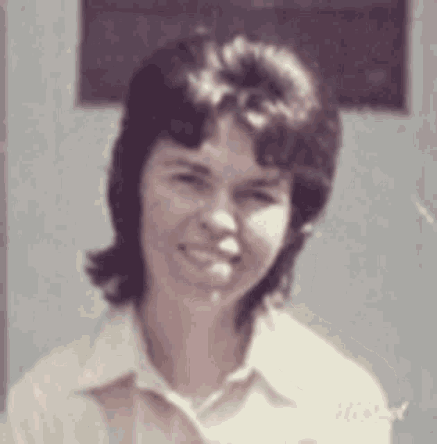 a woman with short hair is smiling for the camera in a purple and white photo .