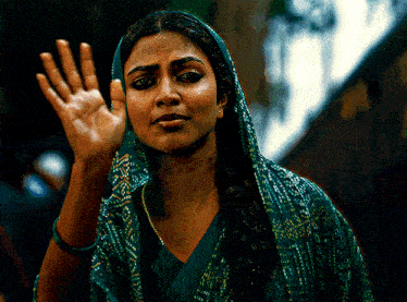 a woman wearing a green scarf on her head waves her hand