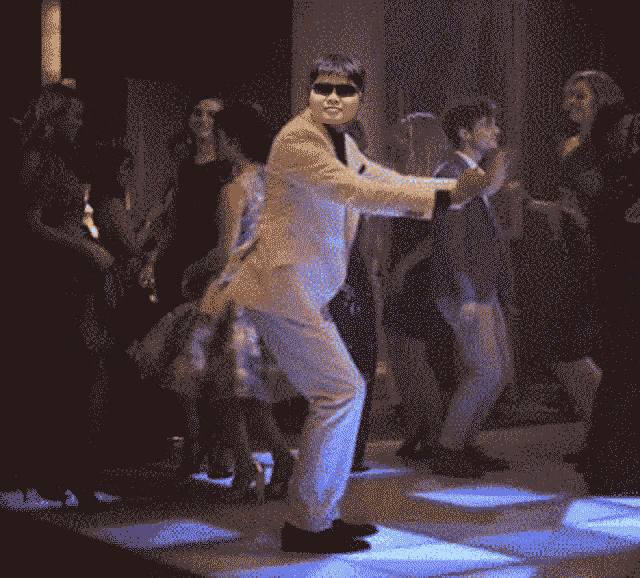 a man wearing sunglasses is dancing on a disco floor