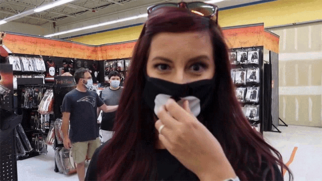 a woman wearing a black face mask wipes her nose with a napkin