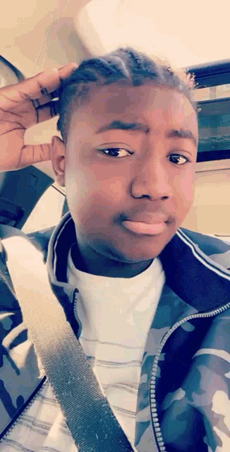 a young man wearing a camo jacket is taking a picture of himself
