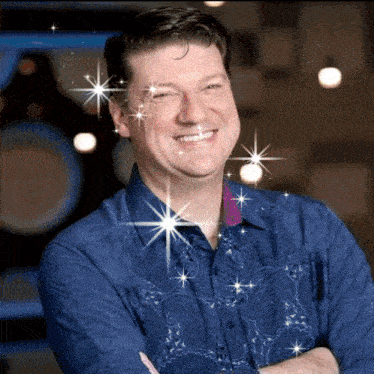 a man in a blue shirt is smiling with sparkles around his face