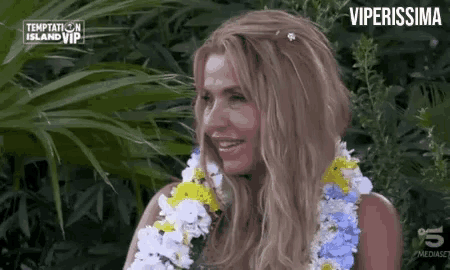 a woman with a lei around her neck is smiling in front of a sign that says temptation island vip .