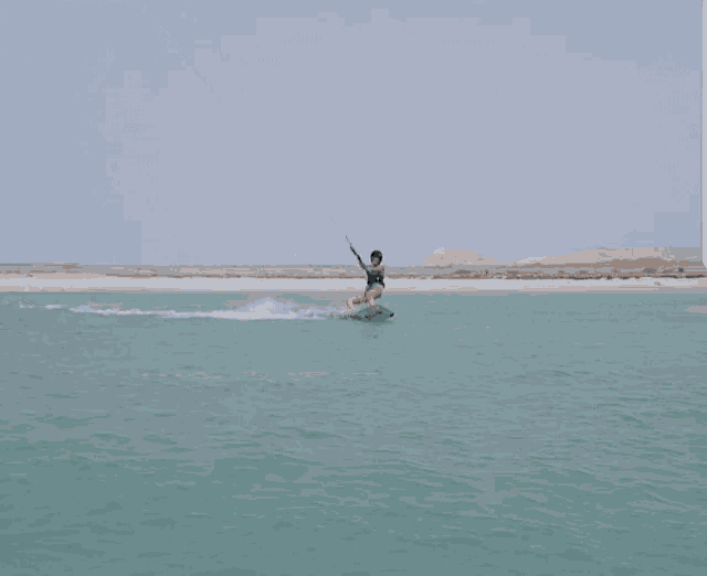 a woman in a bathing suit is riding a surfboard in the ocean