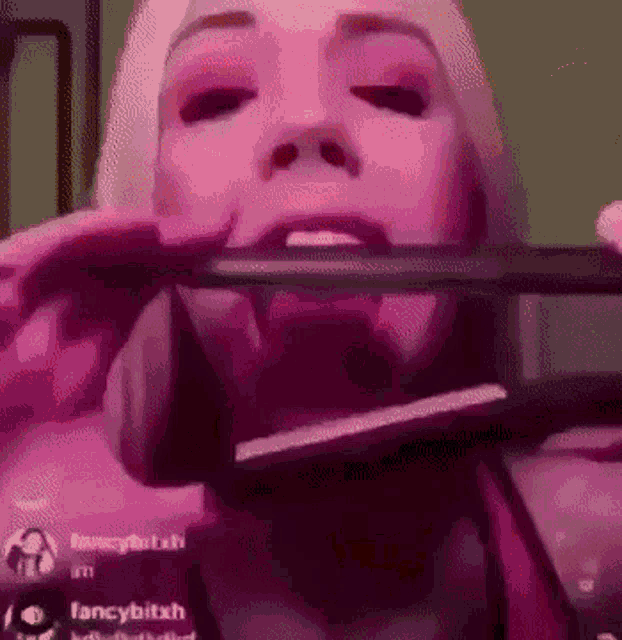 a woman is holding a hair straightener in her mouth while wearing pink makeup .