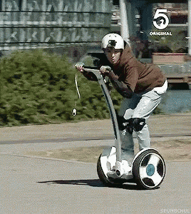a person is riding a segway on a street with a 5 original logo in the background