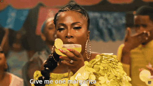 a woman in a yellow dress holds a margarita in her hand