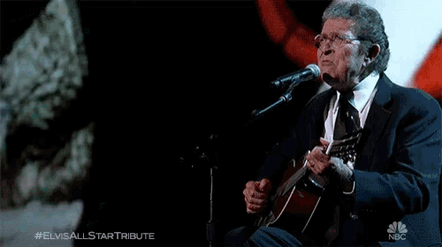 a man playing a guitar and singing into a microphone with the elvis all star tribute written on the bottom
