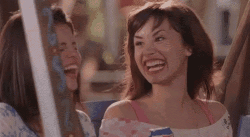 two women are sitting next to each other on a bus laughing .