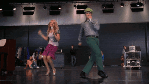 a man and a woman singing into microphones on a stage in front of a boombox