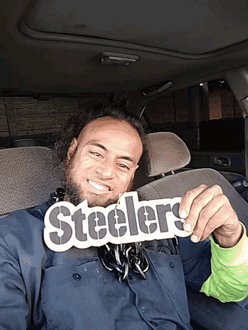 a man in a car holds up a steelers sign