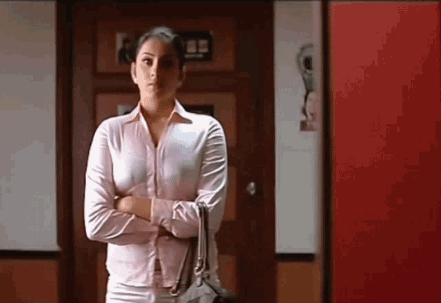 a woman with her arms crossed is standing in front of a red door