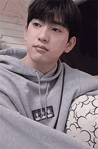 a young man is sitting on a couch wrapped in a blanket .