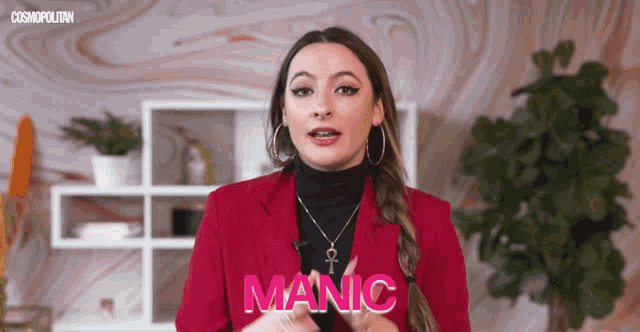 a woman in a red jacket and black turtleneck is talking about manic