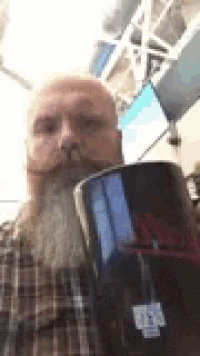 a man with a beard and mustache is holding a mug in his hand .