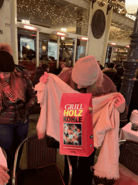 a bag of grill holz kohle is being held by two women