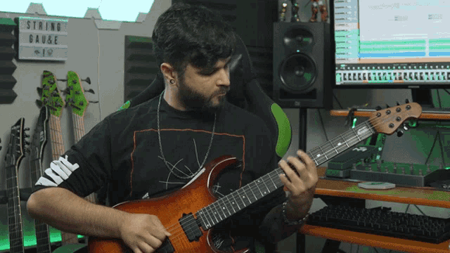 a man playing a guitar in front of a sign that says string gauge on it