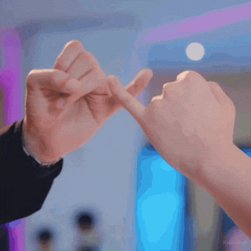a man and woman making a pinky promise with their hands