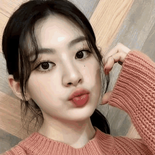 a woman wearing a pink sweater is making a face