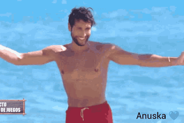 a shirtless man stands on the beach with his arms outstretched in front of a sign that says proyecto de juegos